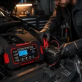 Cargador Inteligente de Baterías5 Cargador RJTianye conectado a la batería de un automóvil en el motor